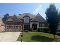 Charming two-story brick home featuring a well-manicured lawn, a two-car garage, and an inviting front porch at 4050 Bonnett Creek Ln, Hoschton, GA 30548