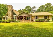 Charming ranch-style home with a stone chimney, inviting front porch, and lush green lawn at 130 Brooklet Way, Brooks, GA 30205