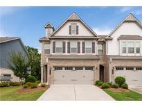 Charming townhome showcasing brick and light-colored siding, a two-car garage, and manicured landscaping at 2169 Lanier Harbor Pt, Buford, GA 30518