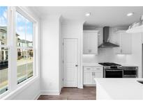 Bright kitchen features white cabinets, stainless steel appliances, subway tile backsplash, and a large window at 628 Skytop Dr # 158, Cumming, GA 30040