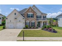 Beautiful two-story home with a well-manicured lawn, stone accents, and a three-car garage at 4035 Starwood Dr, Cumming, GA 30028