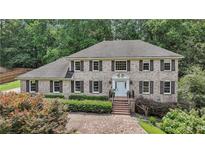 Traditional brick home featuring a manicured lawn, brick driveway, shutters, and a welcoming front door at 5349 Forest Springs Dr, Dunwoody, GA 30338