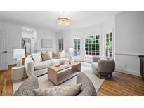 Bright living room with a neutral color palette and a large bay window showcasing the outdoor greenery at 1017 Mill Creek Ne Mnr, Brookhaven, GA 30319