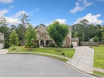 Charming two-story home with stone accents, a well-manicured lawn, and a long driveway leading to a side-entry garage at 2767 Nw Magnolia Creek Dr, Kennesaw, GA 30152