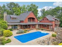 Stunning exterior view of the home with a beautiful pool and a patio area, surrounded by lush greenery at 150 Henderson Farm Dr, Woodstock, GA 30188