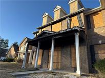 Brick townhome with boarded-up windows and fire damage on the porch and roofline at 1980 Piedmont Pointe Dr, Lithonia, GA 30058