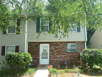 Charming townhome featuring a brick facade, complemented by well-manicured landscaping and leafy trees at 8959 Stonebridge Blvd, Douglasville, GA 30134