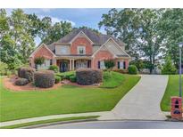 Charming two-story brick home with a well-manicured lawn, lush landscaping, and a long driveway at 3217 Aberrone Pl, Buford, GA 30519