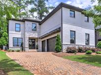 Charming two-story home with a brick driveway and a combination of white painted brick and stone facade at 913 Sunny Meadows Ln, Marietta, GA 30062