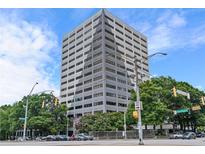 Tall building featuring a gray facade, surrounded by greenery, blue skies and street-level cars at 120 Ralph Mcgill Ne Blvd # 1409, Atlanta, GA 30308
