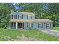 Charming two-story home with blue siding, black shutters, attached garage, and a well-manicured front lawn at 5242 Mccarter Sta, Stone Mountain, GA 30088