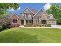 Inviting two-story home boasts a brick and stone facade, manicured lawn, and professionally landscaped garden at 5114 Brendlynn Dr, Suwanee, GA 30024