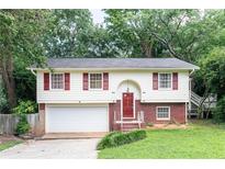 Charming two-story home with red shutters, brick accents, attached garage, and mature trees, providing great curb appeal at 2831 Carolyn Se Dr, Smyrna, GA 30080