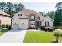 Charming two-story home with a manicured front yard, three-car garage, stone accents, and covered entrance at 4171 Lantern Hill Dr, Dacula, GA 30019