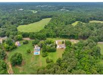 A beautiful aerial view of a home surrounded by lush greenery and a nearby meadow, creating a serene and private setting at 4444 Cannon Sw Rd, Loganville, GA 30052