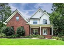 Charming brick and siding home with covered front porch and well-maintained landscaping at 90 Barrington Grange Dr, Sharpsburg, GA 30277
