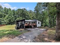 Unique home with a modern black and white exterior design nestled amongst mature trees at 140 Indian Lake Dr, Hiram, GA 30141