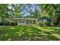 Charming one-story home with yellow brick, blue trim, mature trees, and a well-manicured lawn at 1729 Norden Rd, Riverdale, GA 30296