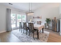Bright dining room features large windows, modern light fixture, and neutral decor at 220 Chandler Ct, Sugar Hill, GA 30518