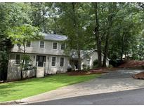 Charming two-story home featuring light siding, well-maintained landscaping, and a welcoming entrance with a set of stairs at 2240 Six Branches Dr, Roswell, GA 30076