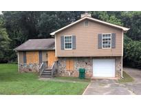 Two-story home with stone accents, wood siding, and some boarded up windows at 3778 Glen Mora Dr, Decatur, GA 30032