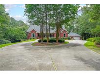 Stately brick home with a circular driveway, mature landscaping, and attached garage nestled on a wooded lot at 750 Old Loganville Road Southwest, Loganville, GA 30052
