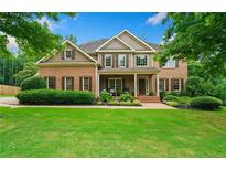 Stunning brick home featuring mature trees, a lush lawn, and a welcoming front porch at 217 Heritage Town Pkwy, Canton, GA 30115