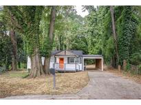 Charming home featuring a covered parking spot and a welcoming front porch with an orange door at 2437 Clarissa Nw Dr, Atlanta, GA 30318