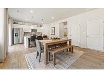 Bright dining area featuring a modern table with bench seating adjacent to a stainless steel kitchen and hardwood flooring at 8504 Polston Lot 145 Pl, Douglasville, GA 30134