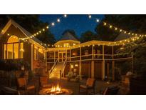 Inviting backyard with fire pit, string lights, covered porch, and exterior stairs at night at 3978 Devonshire Dr, Marietta, GA 30066