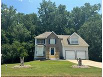 Charming two-story home featuring a two-car garage, a manicured lawn, and a welcoming blue front door at 4148 Kings Cswy, Ellenwood, GA 30294