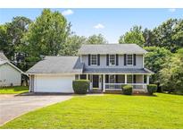 Charming two-story house with a well-manicured lawn and a welcoming front porch with white railings at 2431 Rosedale Creek Dr, Snellville, GA 30078