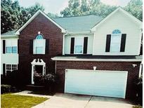 Charming two-story home with brick and vinyl siding, a well-manicured lawn, and an attached two-car garage at 3233 Rockmill Dr, Ellenwood, GA 30294