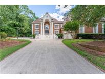 Striking two-story brick home with columns and a spacious front yard, offering a grand and inviting appeal at 5435 Chelsen Wood Dr, Duluth, GA 30097