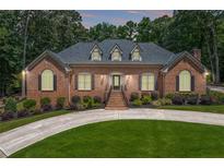 Beautiful single-story brick home with manicured lawn and inviting circular driveway and lush landscaping at 2065 Innsfail Dr, Snellville, GA 30078
