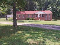 Charming brick home features a red roof, a columned front porch and a beautifully landscaped yard at 6005 Hendrix Rd, Cumming, GA 30040