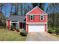 Charming red two-story home with a well-manicured lawn and two-car garage at 7472 Woods Ct, Lithonia, GA 30058