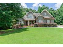 Charming two-story home features a well-manicured lawn, lush landscaping, and inviting entrance with covered front porch at 1404 Fairwinds Ct, Loganville, GA 30052