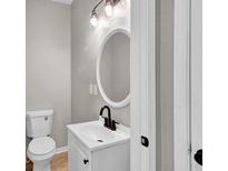 Charming bathroom featuring a white vanity, an oval mirror and modern lighting fixtures at 583 Whitaker St, Atlanta, GA 30318