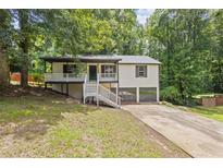 Charming home featuring a welcoming porch, two car garage and mature trees at 6441 Michell Way, Douglasville, GA 30135