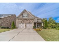 Charming two-story home with a stone and siding facade, two-car garage, and well-manicured lawn at 5960 Overlook Club Cir, Suwanee, GA 30024