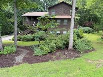 Charming two-story home with brown siding, front porch, and mature landscaping in a wooded setting at 3470 Hill Ln, Acworth, GA 30102