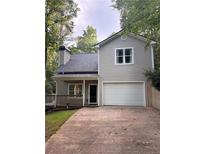 Charming home featuring a 2-car garage and covered porch surrounded by lush greenery at 3255 Marine Rd, Cumming, GA 30041