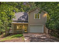 Charming home featuring a one-car garage and a cozy front porch, surrounded by lush trees at 3255 Marine Rd, Cumming, GA 30041