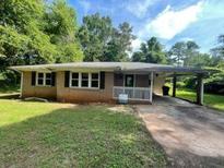 Cozy single-story home with a brick facade, large windows, and a covered carport on a partially sunny day at 2369 Christian Cir, Covington, GA 30016