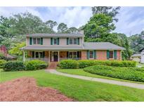 Charming two-story home with brick facade, green shutters, a welcoming porch, and lush landscaping at 2291 Smokehouse Path, Lawrenceville, GA 30044