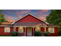 Charming red house with a lovely front porch, trimmed in white, under a picturesque sky at 7880 Rivertown Rd, Fairburn, GA 30213