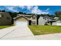 Two-story home with green siding, two-car garage, and a well-manicured lawn and landscape at 4417 Belcamp Rd, Fairburn, GA 30213