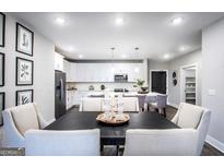 Bright dining area showcases a table setting with a view to the modern kitchen and white cabinetry at 3351 Orwell Way # 2301, Cumming, GA 30041