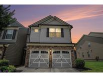 Charming townhome featuring a stone facade and two-car garage with decorative doors against a twilight sky at 252 Stone Park Dr, Woodstock, GA 30188
